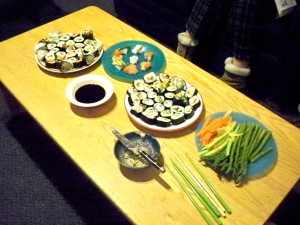 Homemade sushi on table with soy sauce and vegetables